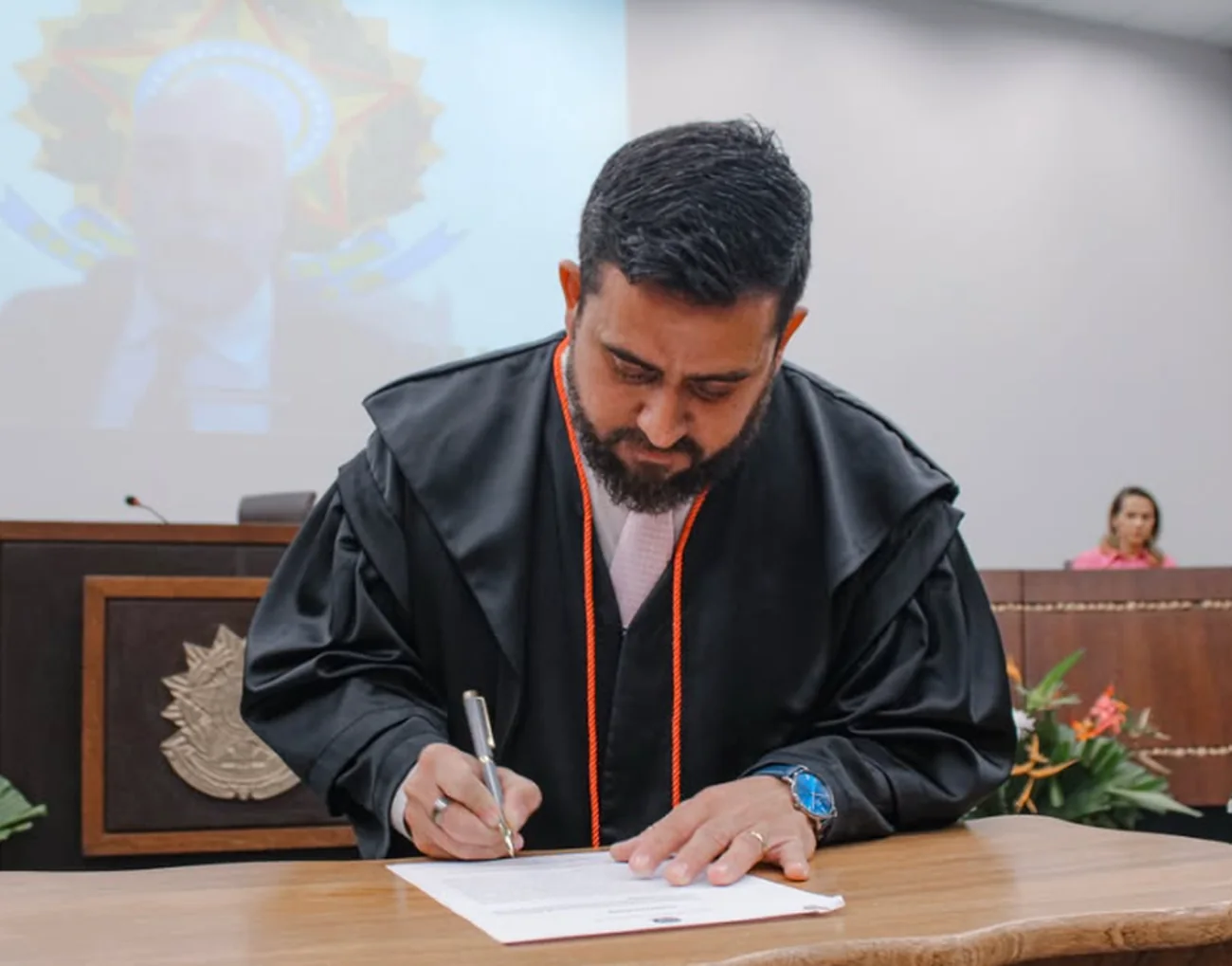 Thalles Sales assinando um documento durante a solenidade do TRE-AC